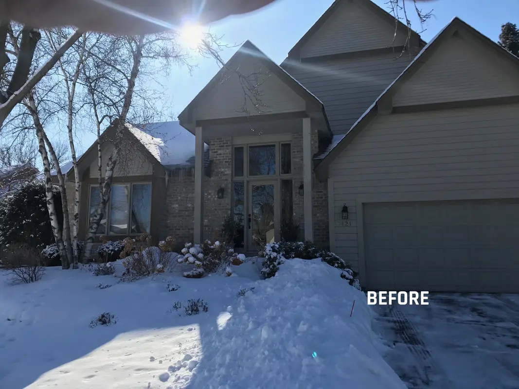 House exterior covered in snow, daytime scene.
