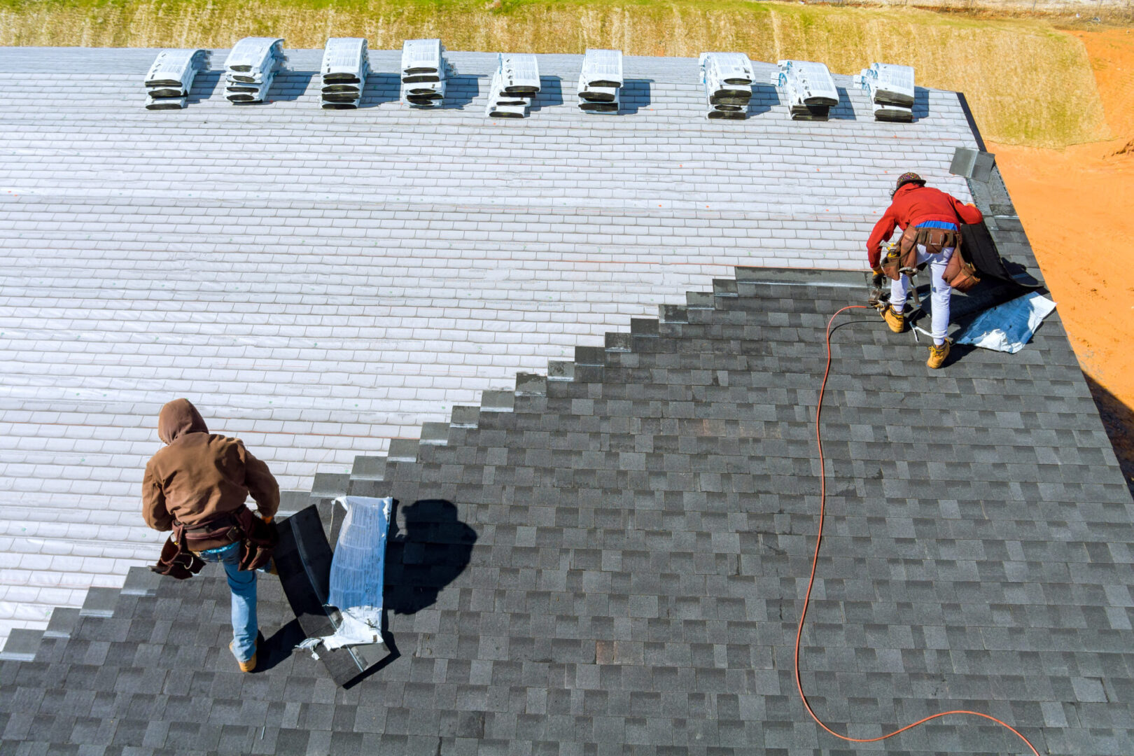 Roofers installing shingles on a rooftop.