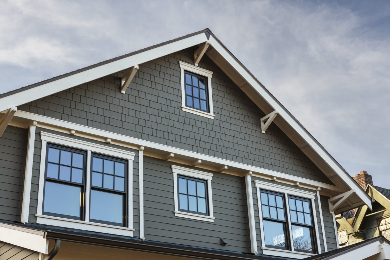 Front Roof line of an Upscale Home House with gray siding and white trim.